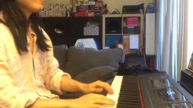 A woman playing a digital keyboard in a cozy home studio setup.