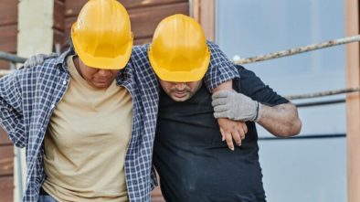 Workers assisting each other on a construction site, emphasizing teamwork and safety.